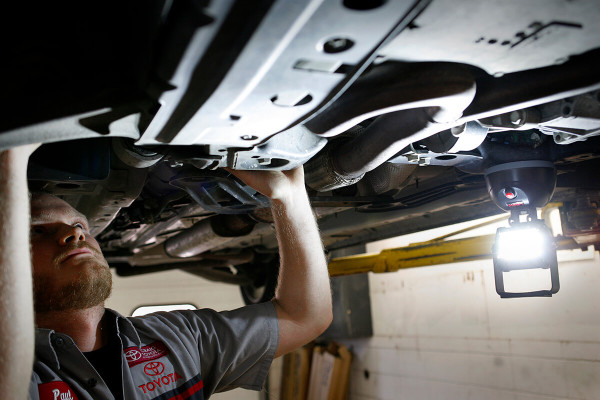 Car mechanic using LED work light under vehicle Car mechanic using LED work light under vehicle